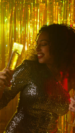 Vertikales-Video-Von-Zwei-Frauen-In-Einem-Nachtclub-Oder-Einer-Bar,-Die-Tanzen-Und-Alkohol-Trinken,-Mit-Funkelnden-Lichtern-Und-Konfetti-Im-Hintergrund